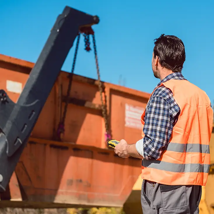Ein Entsorgungsmitarbeiter bei der Verladung eines Müllcontainers mit Sperrmüll